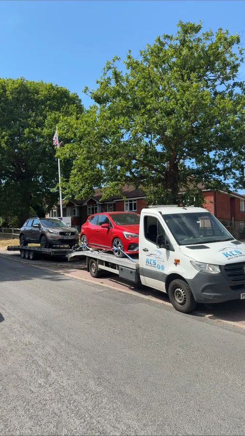 KCS transporter carrying two vehicles on a sunny residential street in Kent